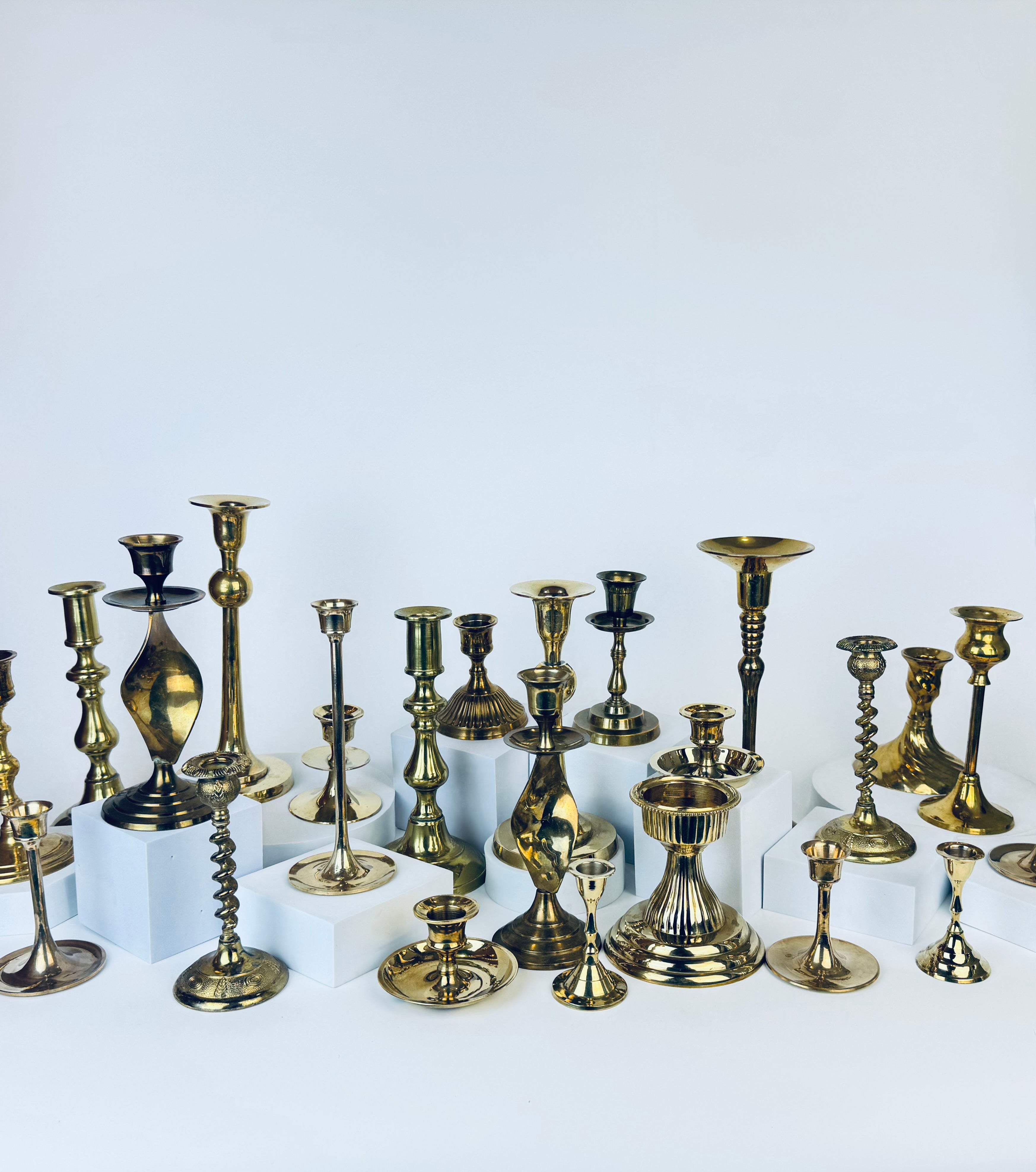 Collection of various brass candle holders on a white background