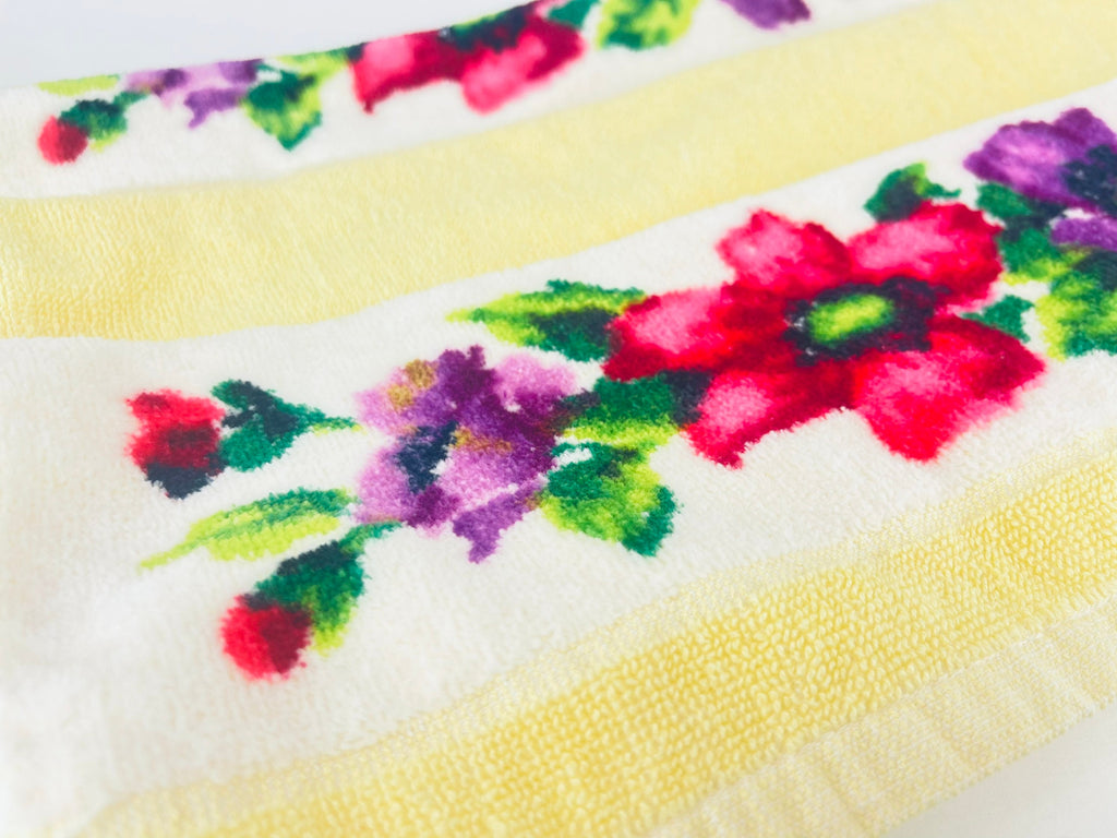 Close-up of a floral patterned fabric with pink, purple, and green flowers on a white background.