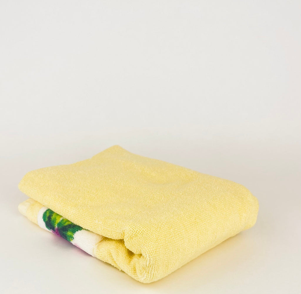 Folded yellow towel with a colorful pattern on a light gray background