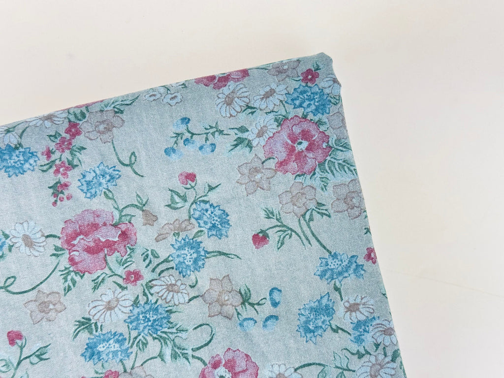Floral fabric with pink, blue, and green flowers on a light blue background