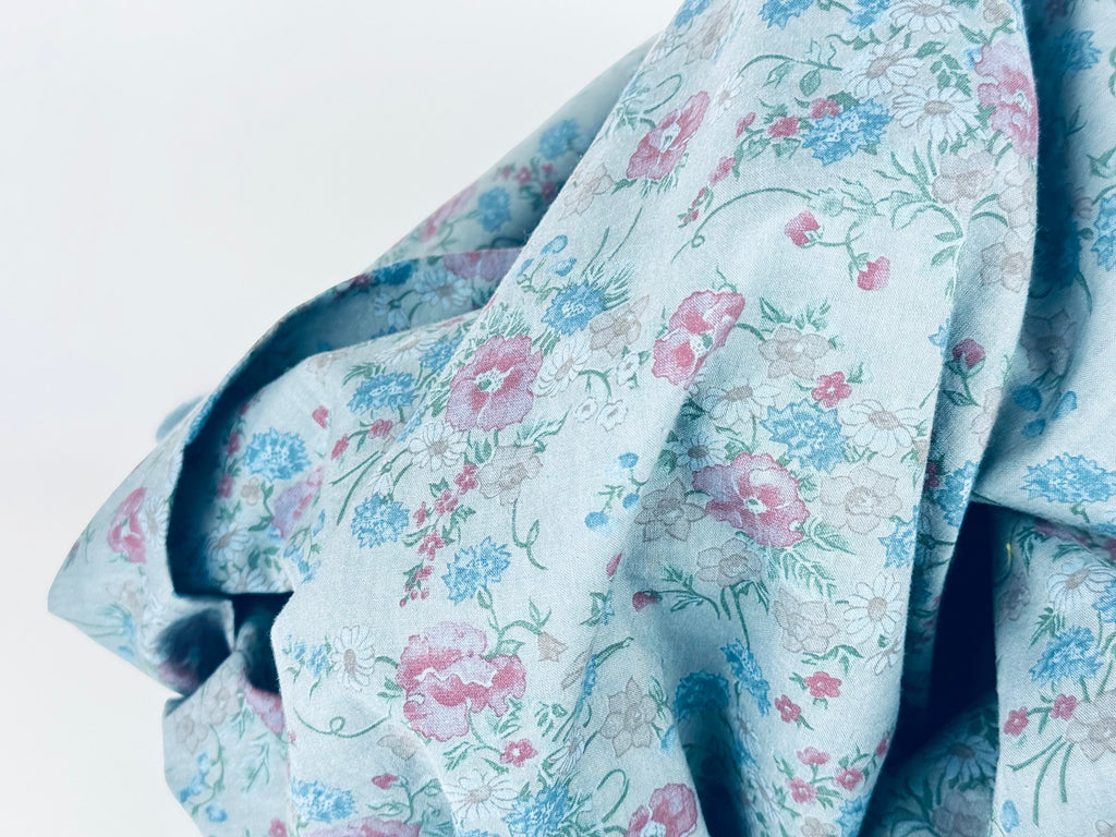 Floral patterned fabric with pink and blue flowers on a light blue background