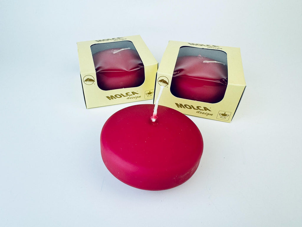 Raspberry candle with a lit wick on a white background, next to its packaging labeled 'Molca'.