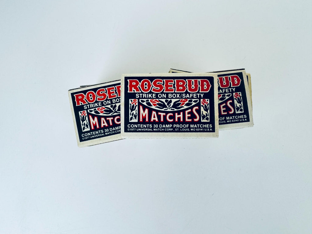 Matchboxes labeled 'Rosebud Matches' on a light gray background