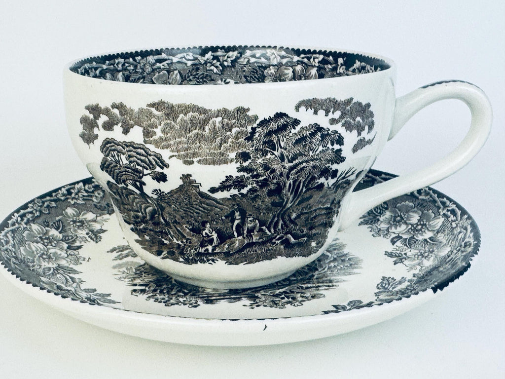 Teacup and saucer with black floral pattern on a white background