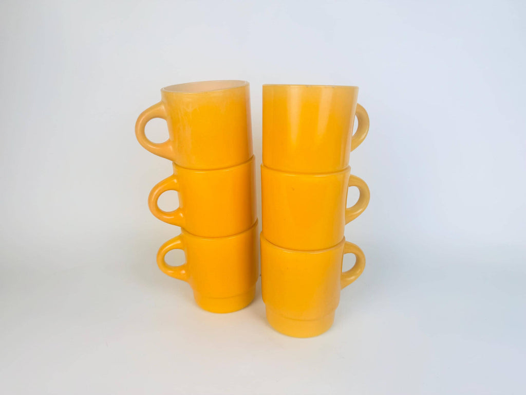 Set of yellow ceramic mugs stacked on a white background