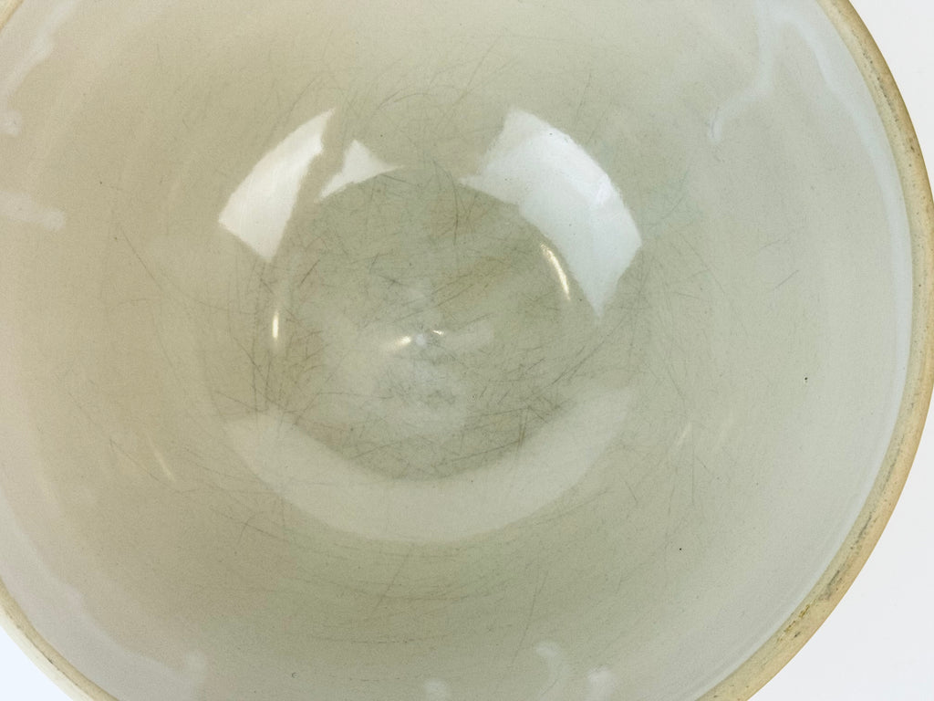 Close-up of a ceramic bowl with a white interior and beige exterior.
