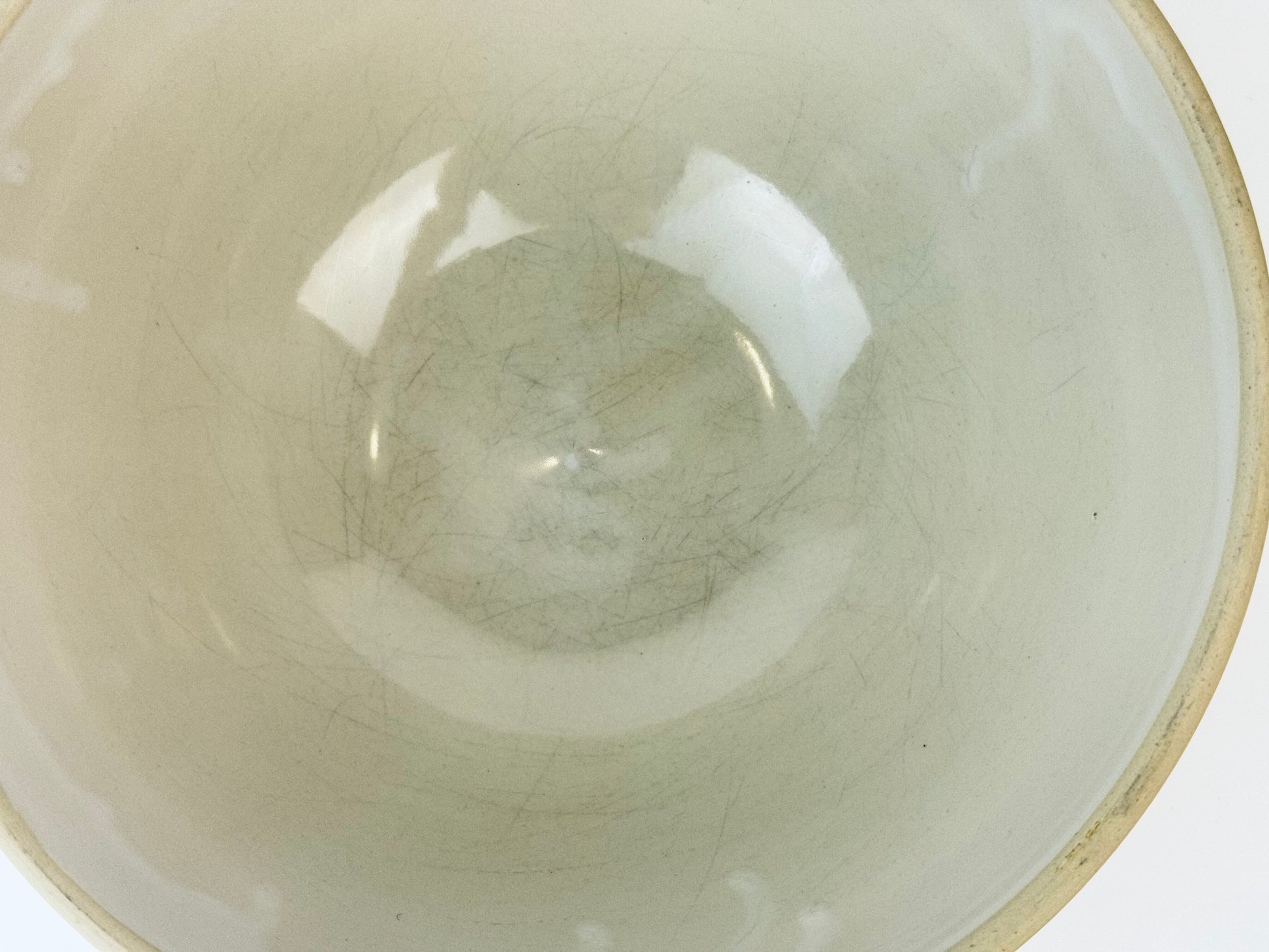 Close-up of a ceramic bowl with a white interior and beige exterior.