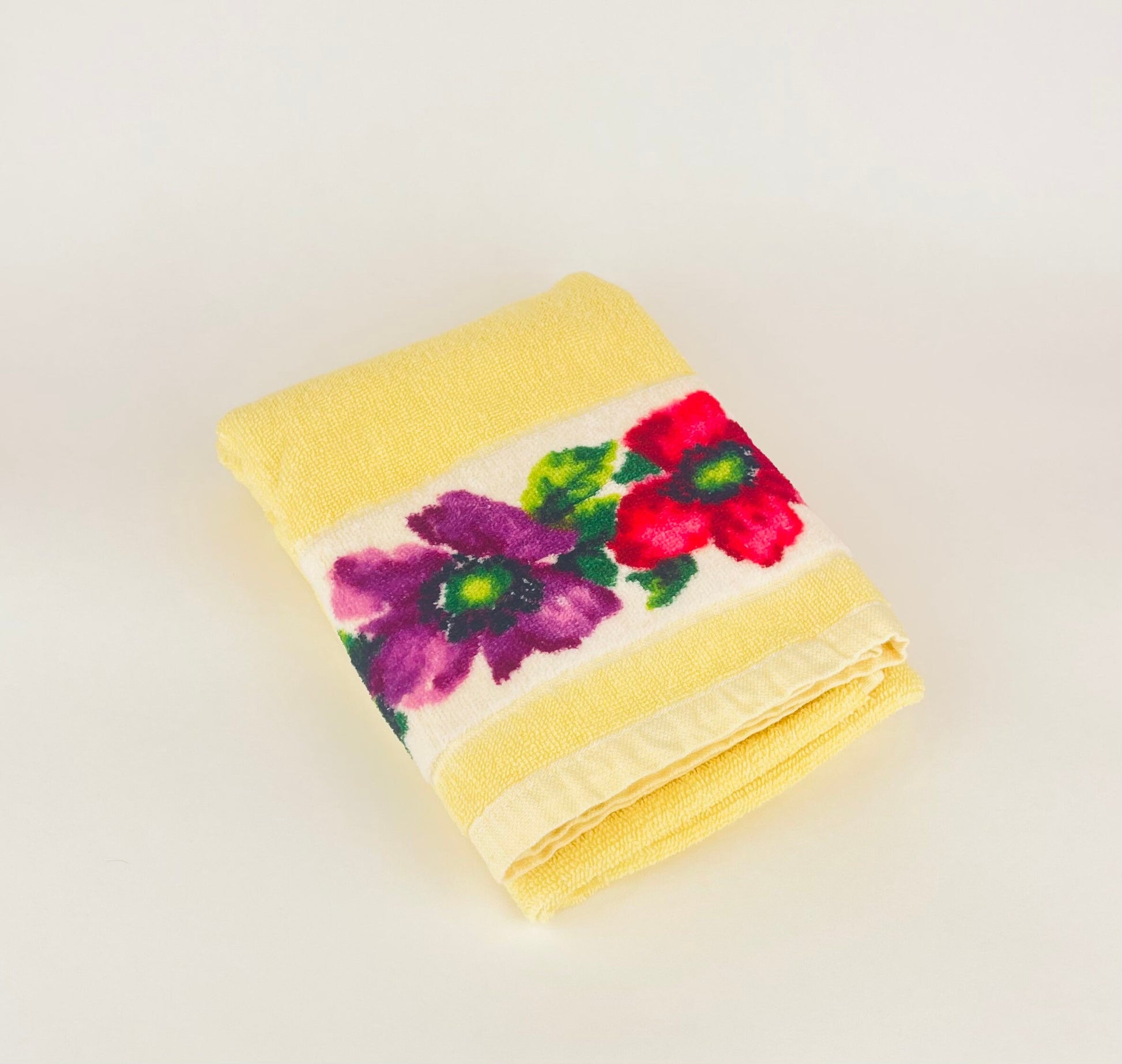 Folded yellow towel with floral pattern on a light background
