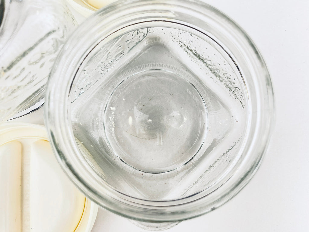 Clear glass jar with a white lid on a light gray background