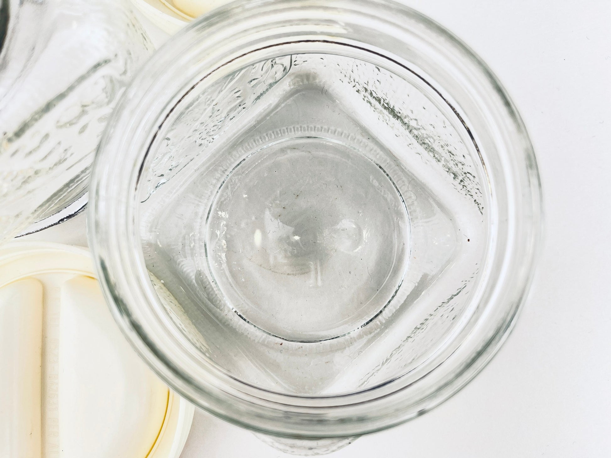 Clear glass jar with a white lid on a light gray background