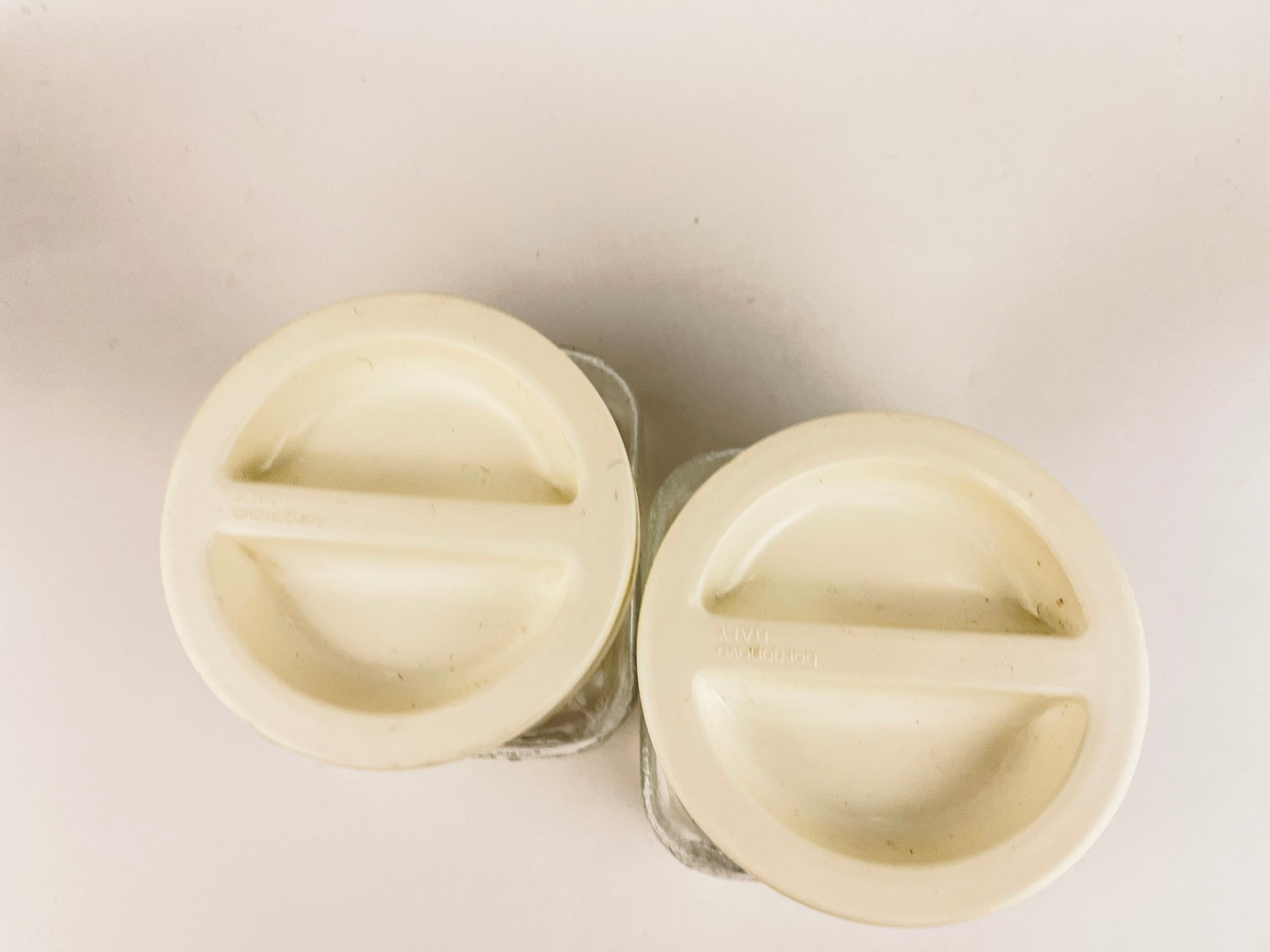 Two white plastic knobs on a light gray background