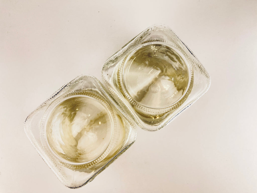 Two small glass containers with a white substance inside on a light background