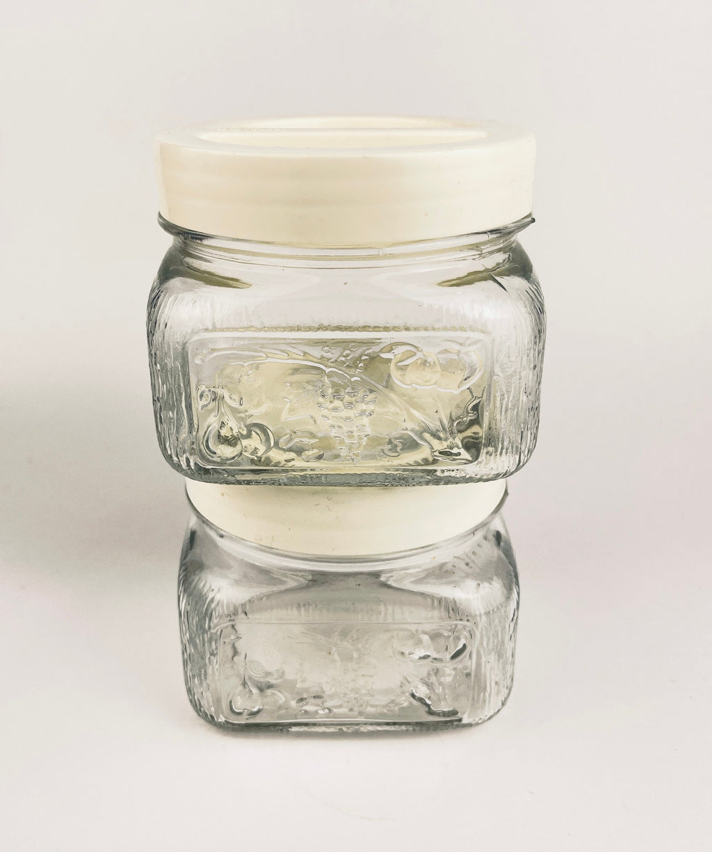 Clear glass jar with a white lid on a light gray background