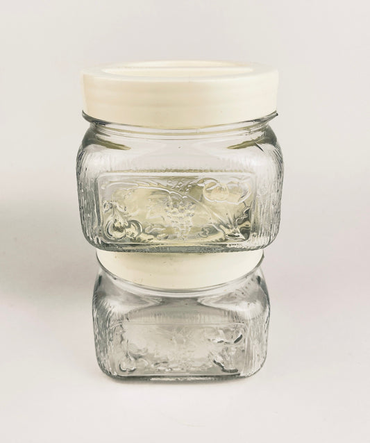 Clear glass jar with a white lid on a light gray background
