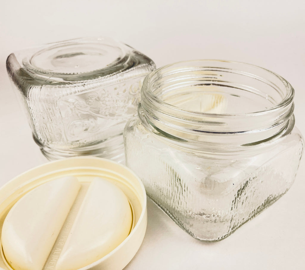 Two clear glass jars with a white lid on a light background