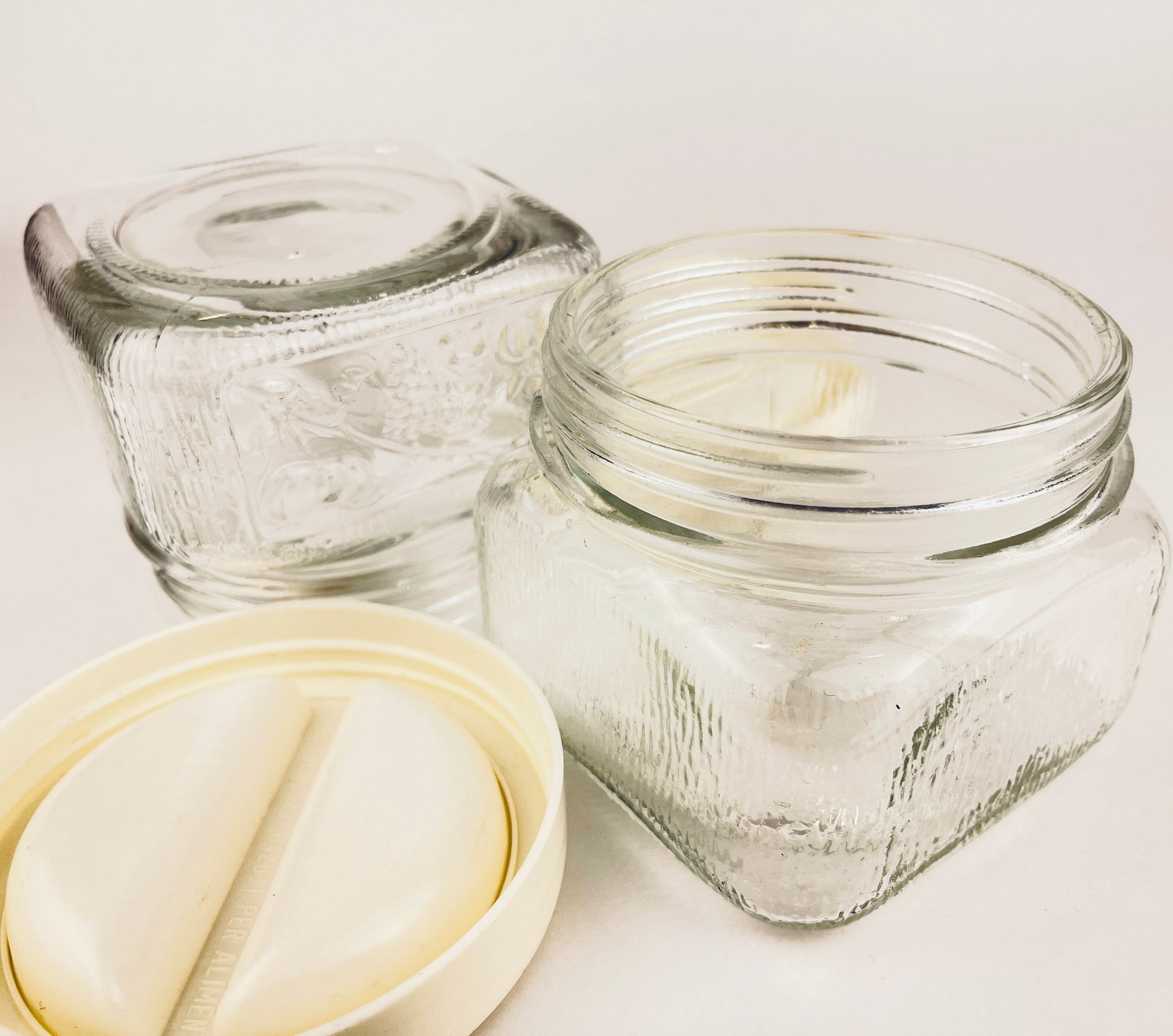 Two clear glass jars with a white lid on a light background