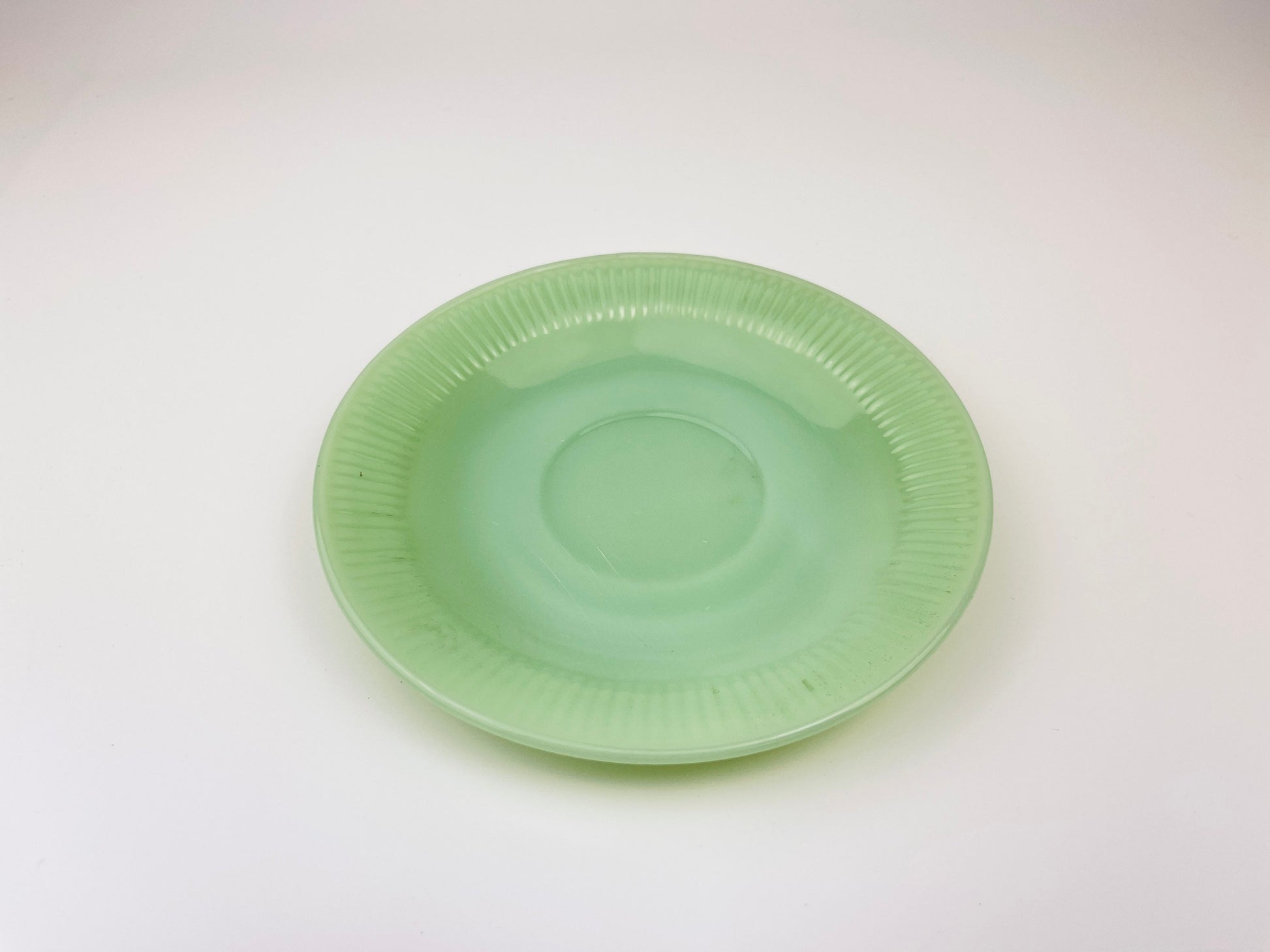 Green jadeite saucer on a white background