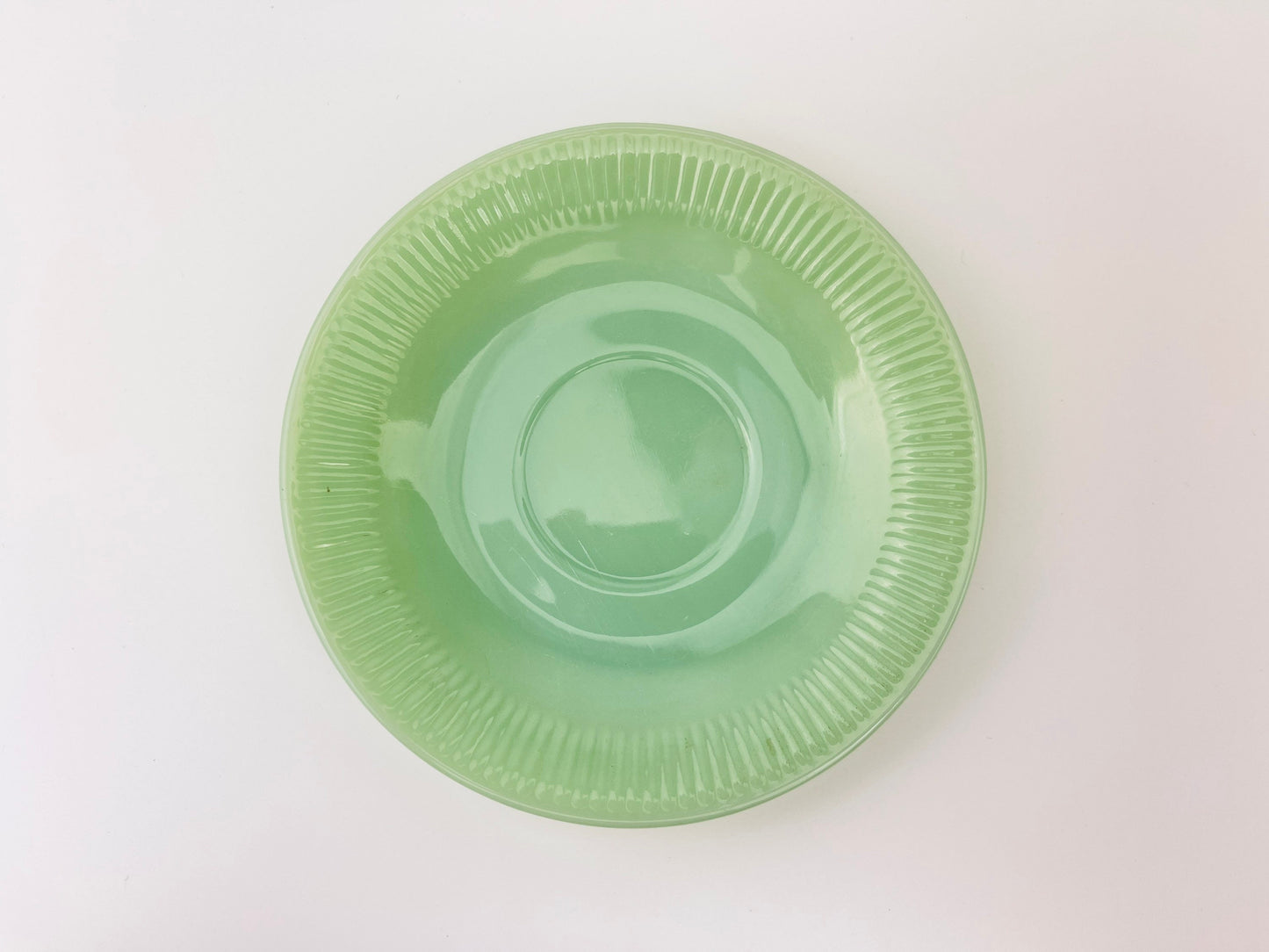 Green jadeite saucer on a white background