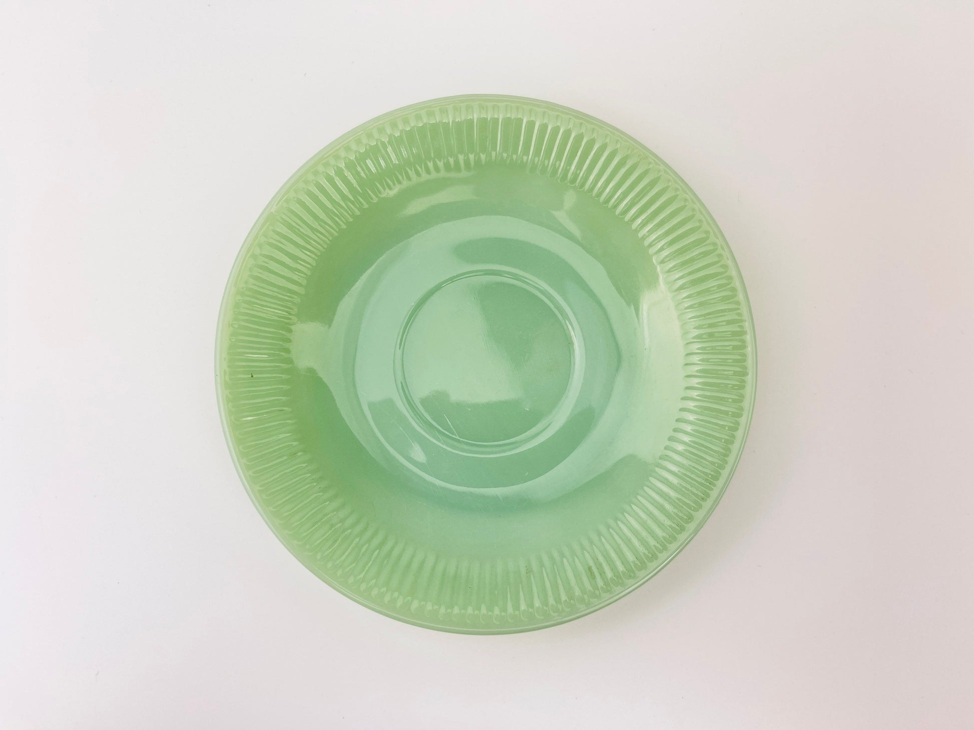 Green jadeite saucer on a white background