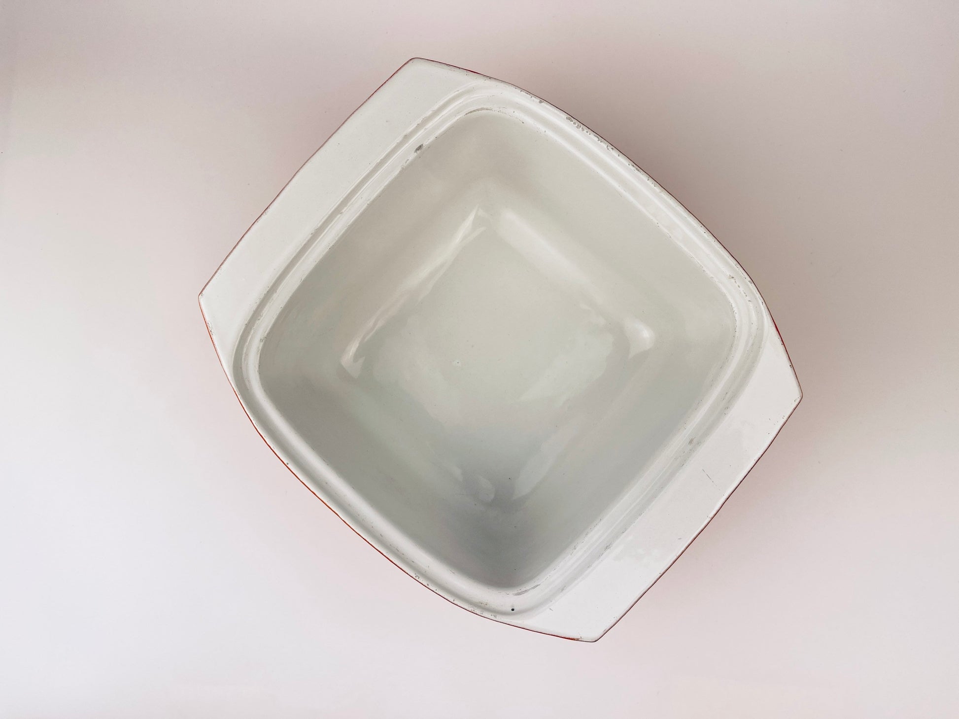White ceramic coated cast iron square bowl on a light beige background
