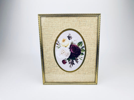 Vintage 1970s gold tabletop picture frame with an 8×10 size and oval interior mat, featuring a textured gold finish and built-in display stand, shown with floral artwork inside.