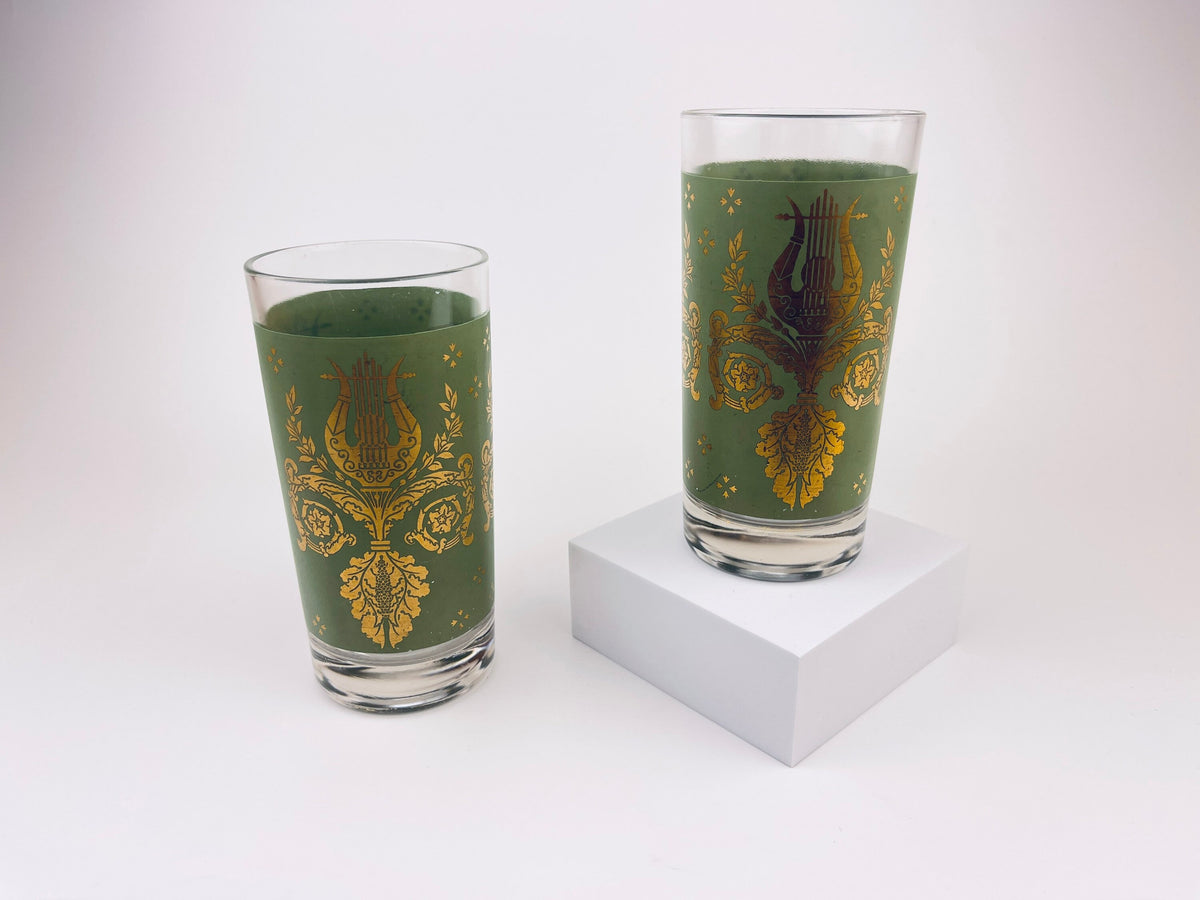 Two green glasses with gold floral patterns on a white background