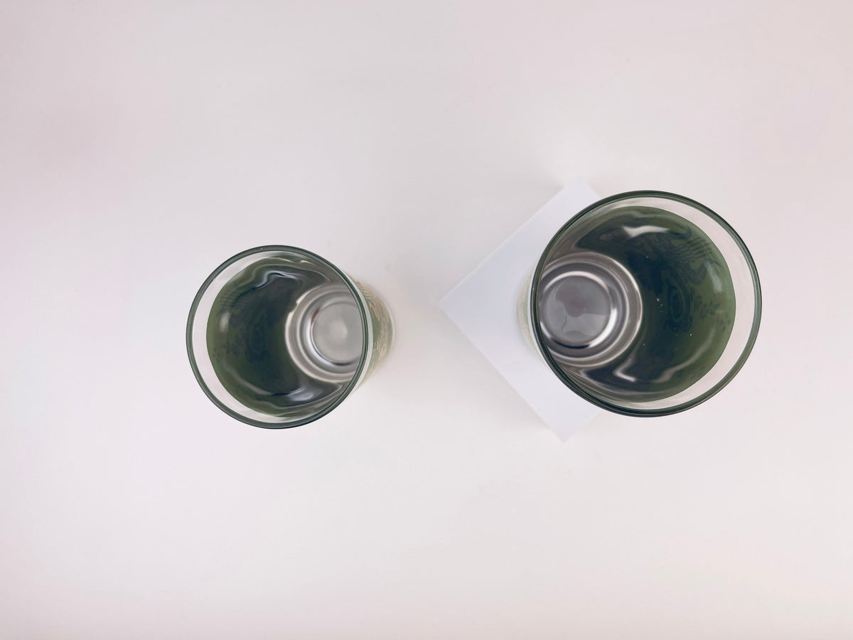 Two glass tumblers with dark liquid on a white background