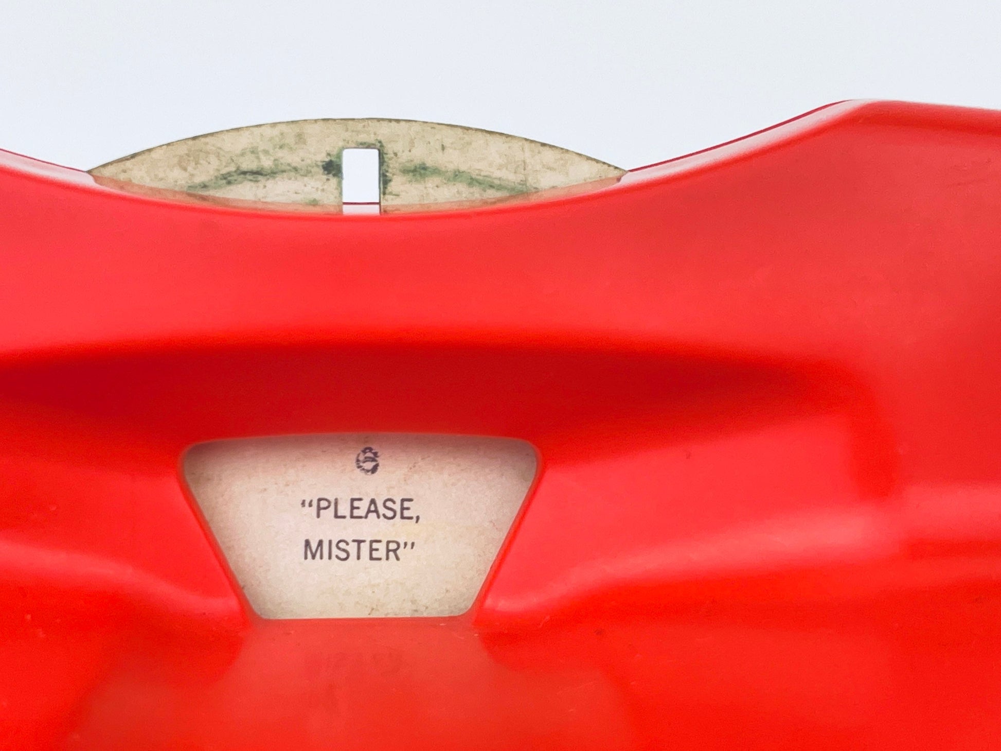 Close-up of a red object with a label inside, featuring text.