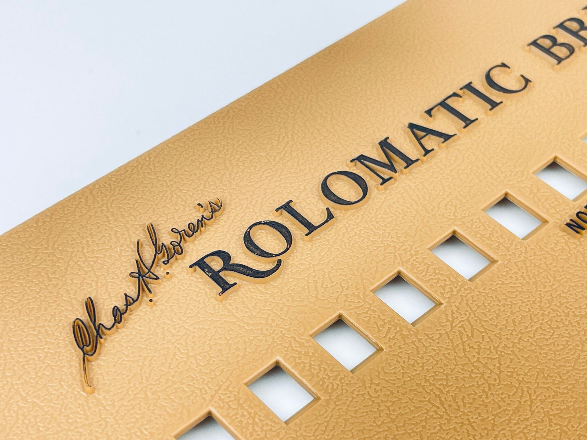 Close-up of a gold product with 'Chas H. Goren's' and 'Rolomatic' branding on a light gray background