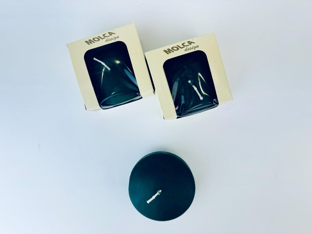 Two green candles in boxes with 'Molca' branding on a white background