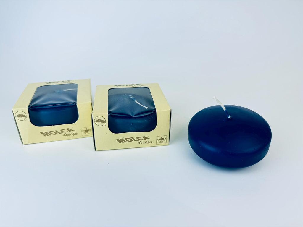Blue candle next to its packaging on a white background