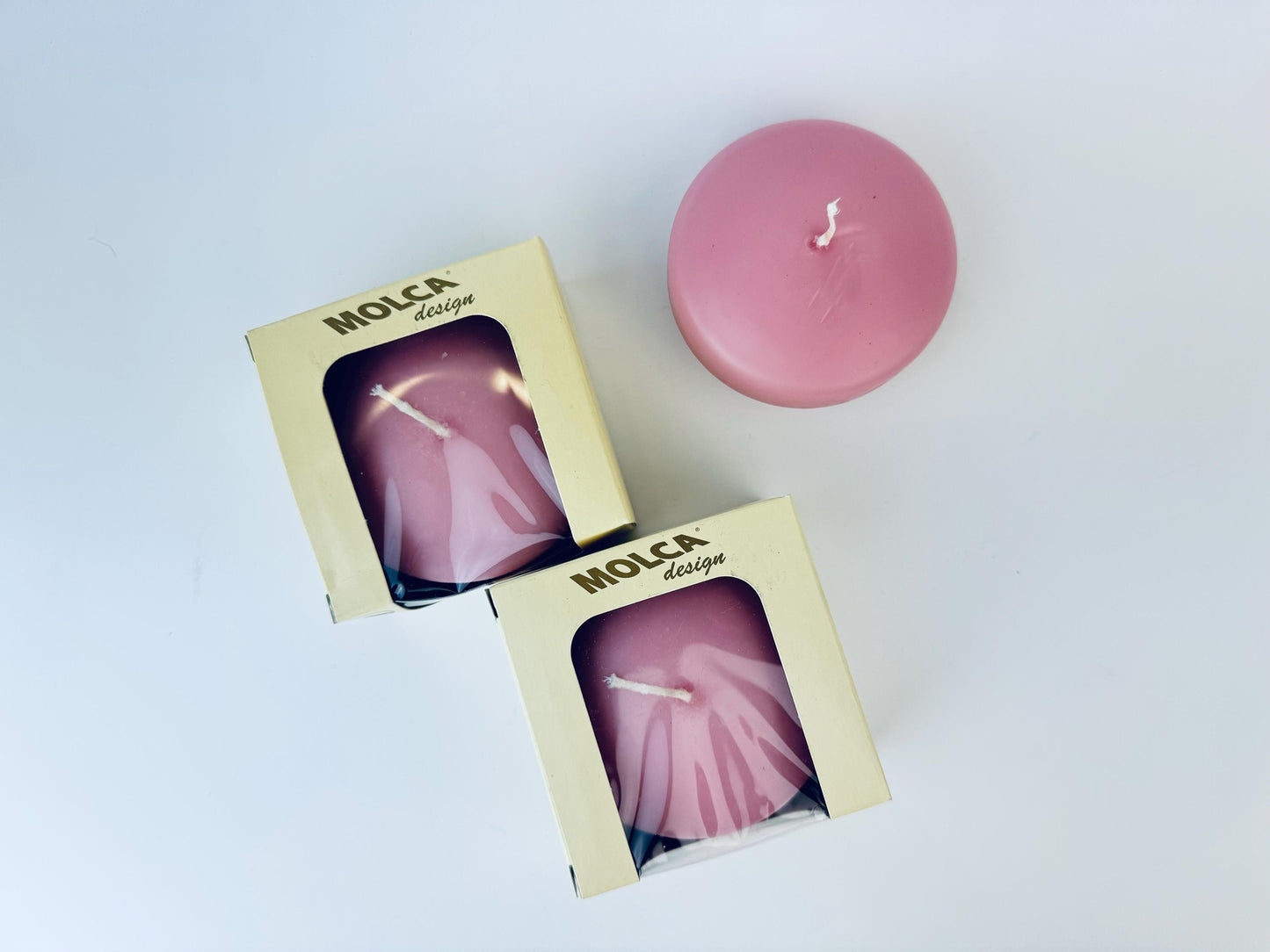 Pink candle with 'Molca' packaging on a light background