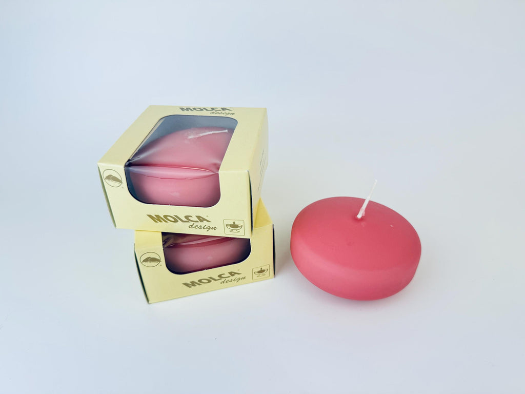 Pink candle with 'Molca' branding next to its packaging on a light gray background