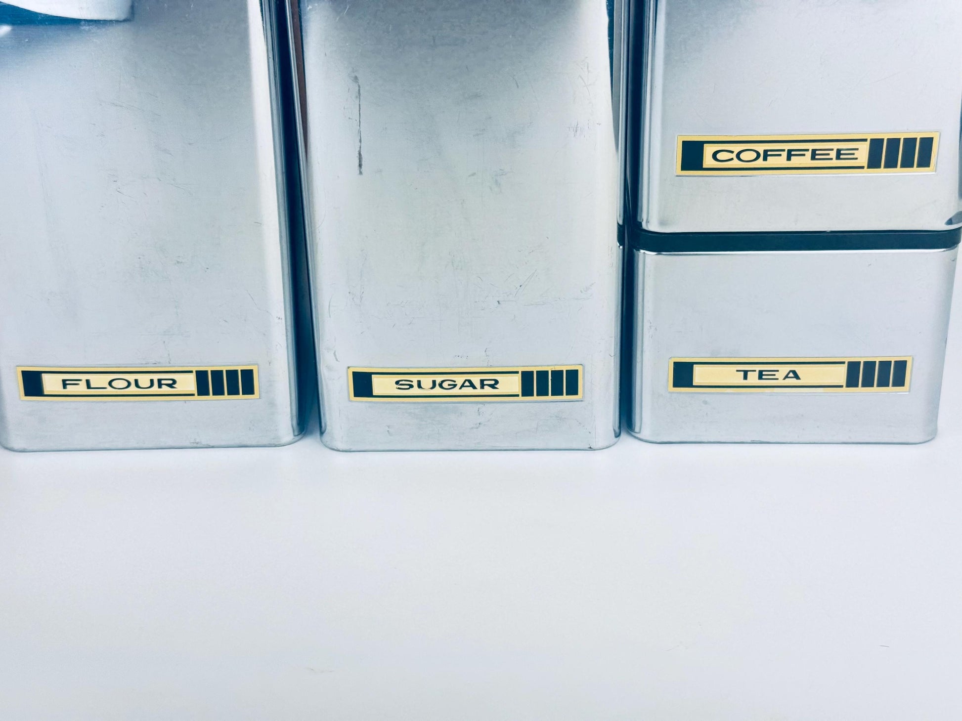 Set of four storage containers labeled 'Flour', 'Sugar', 'coffee' and 'Tea' on a white background.