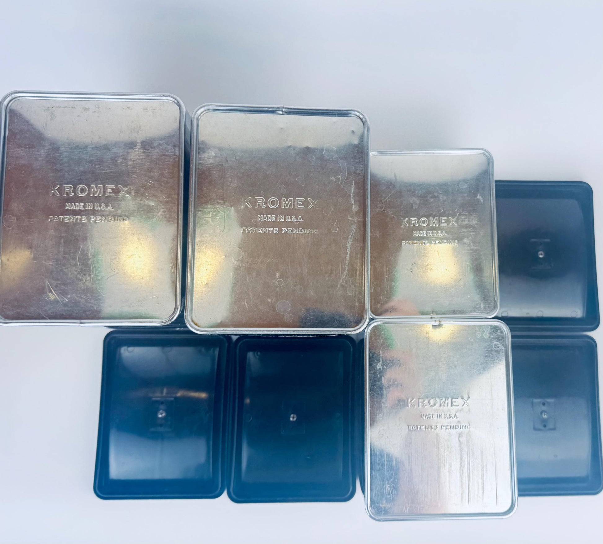 Collection of Kromex metal containers on a white background