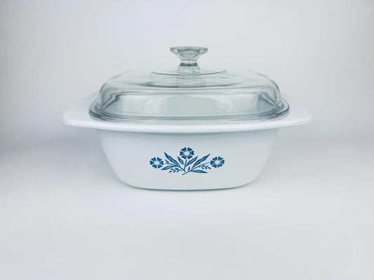 White Corning Ware dutch oven dish with the blue cornflower pattern and clear lid on a white background
