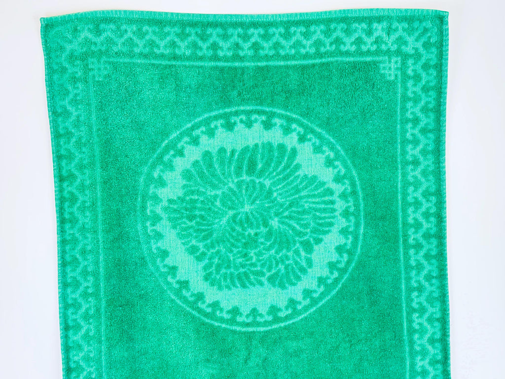 Green towel with a circular pattern and border on a white background