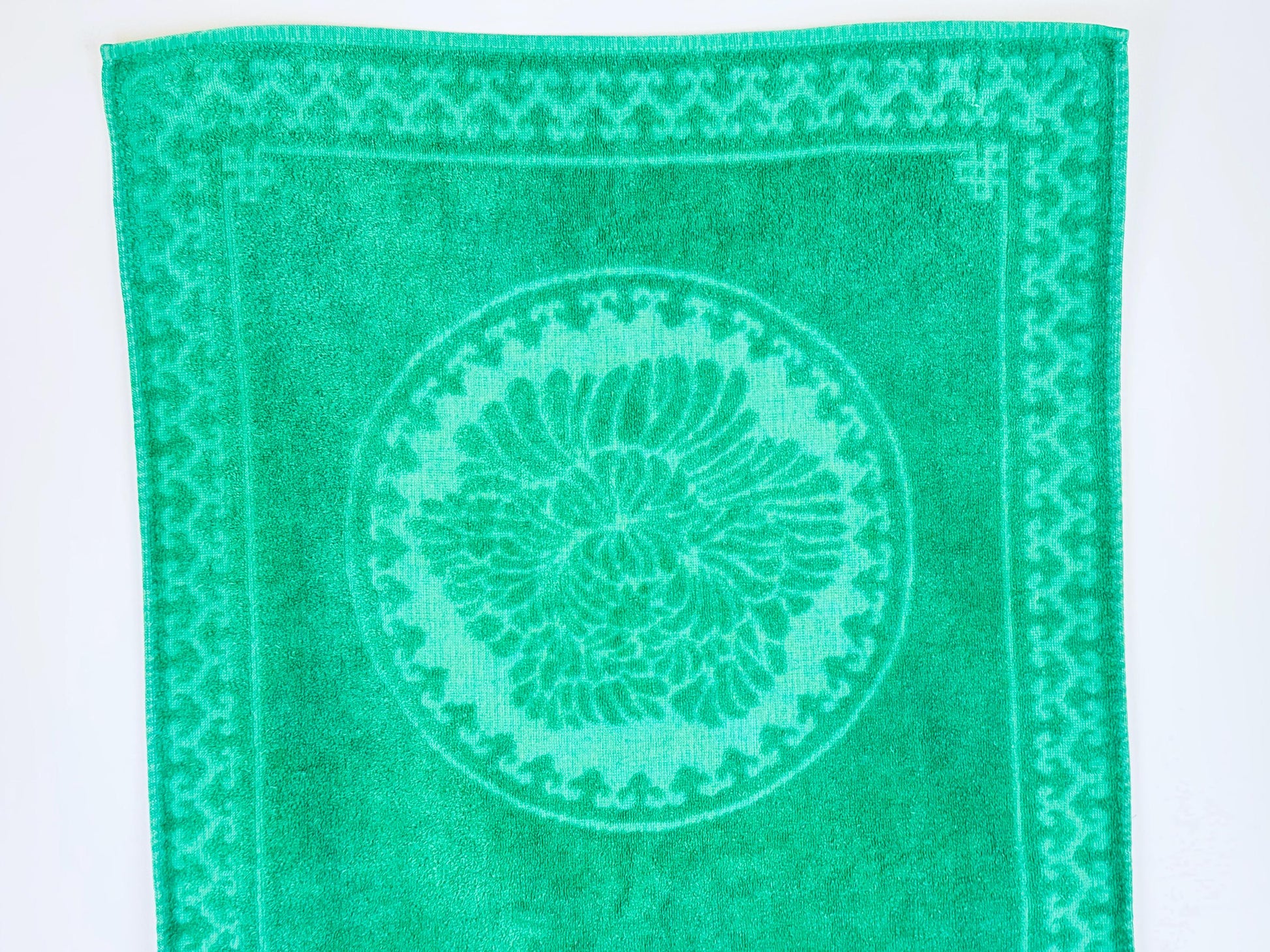 Green towel with a circular pattern and border on a white background