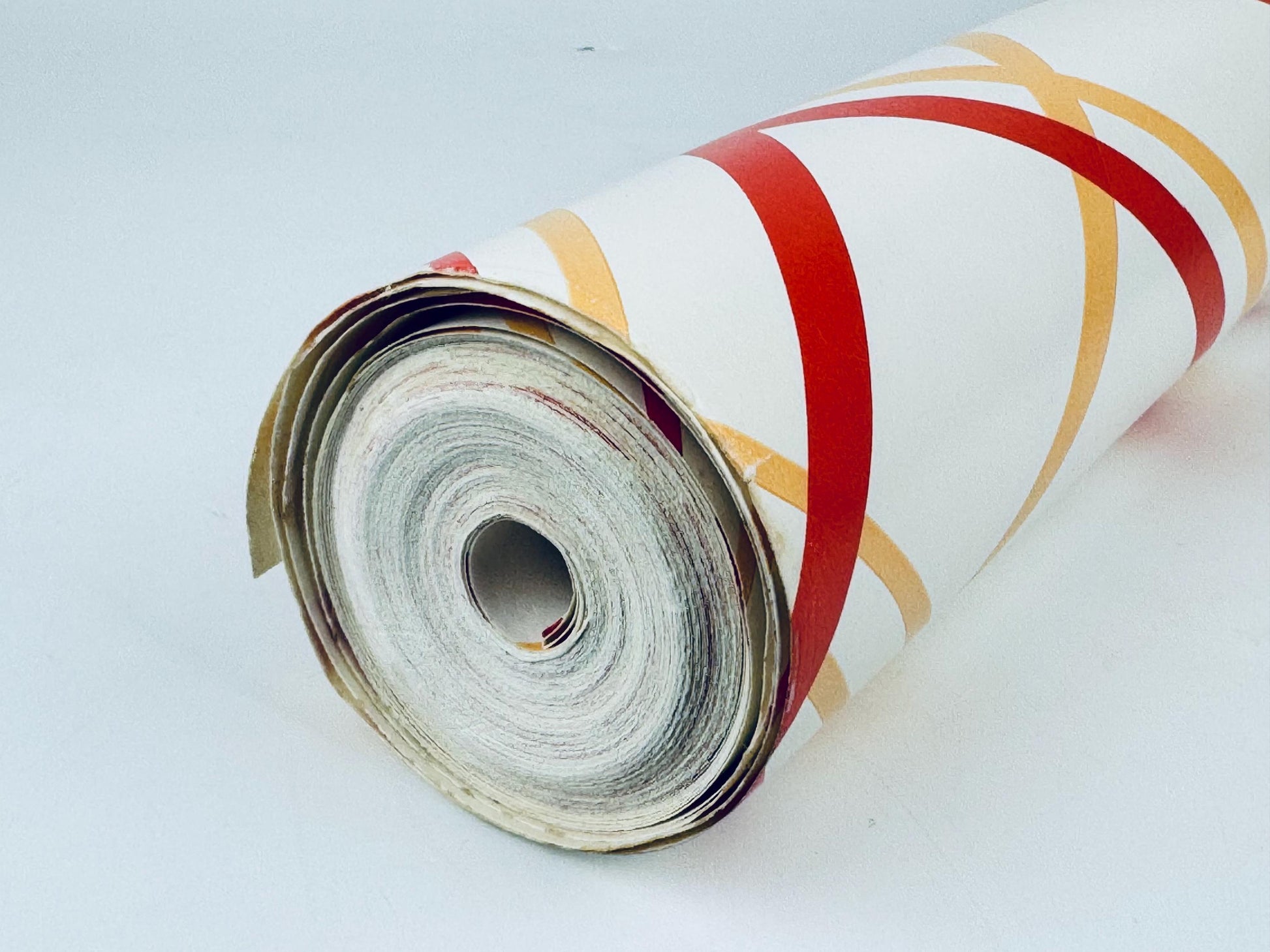 Roll of decorative paper with red and gold patterns on a white background