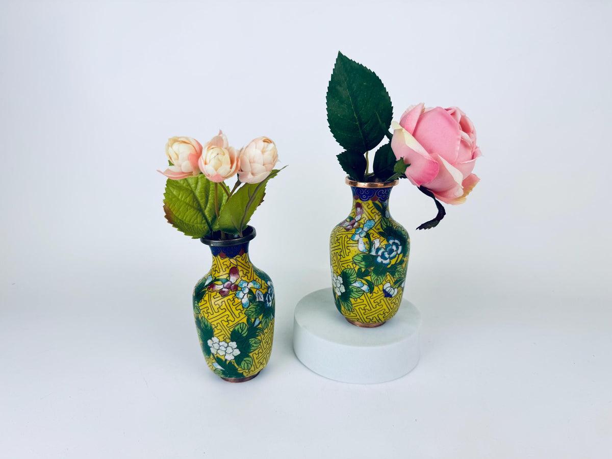 Two decorative vases with floral arrangements on a white background