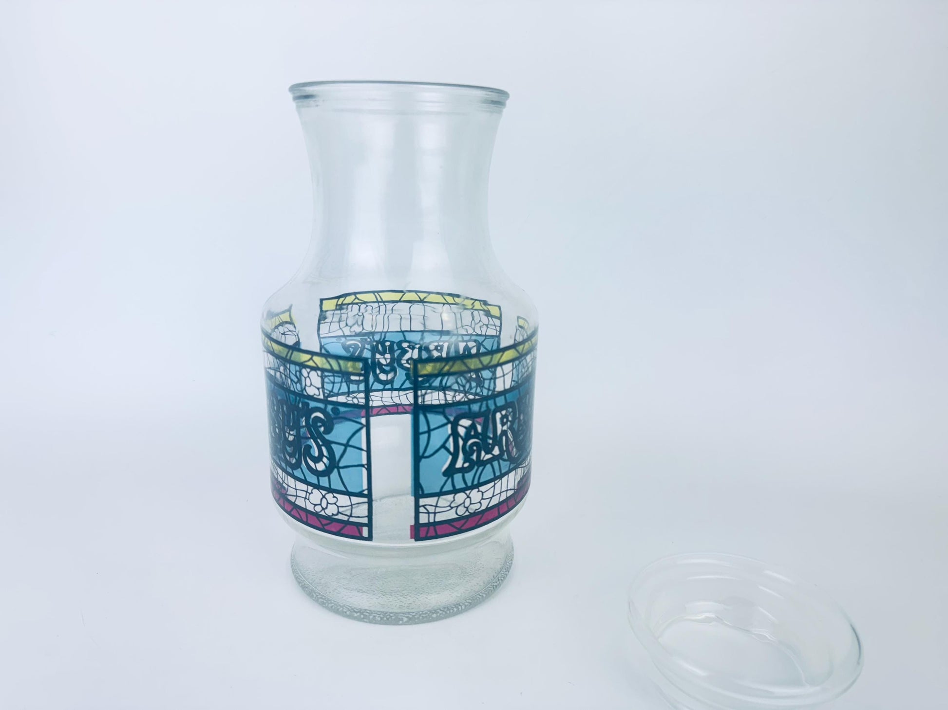 Clear glass carafe with colorful design on a white background