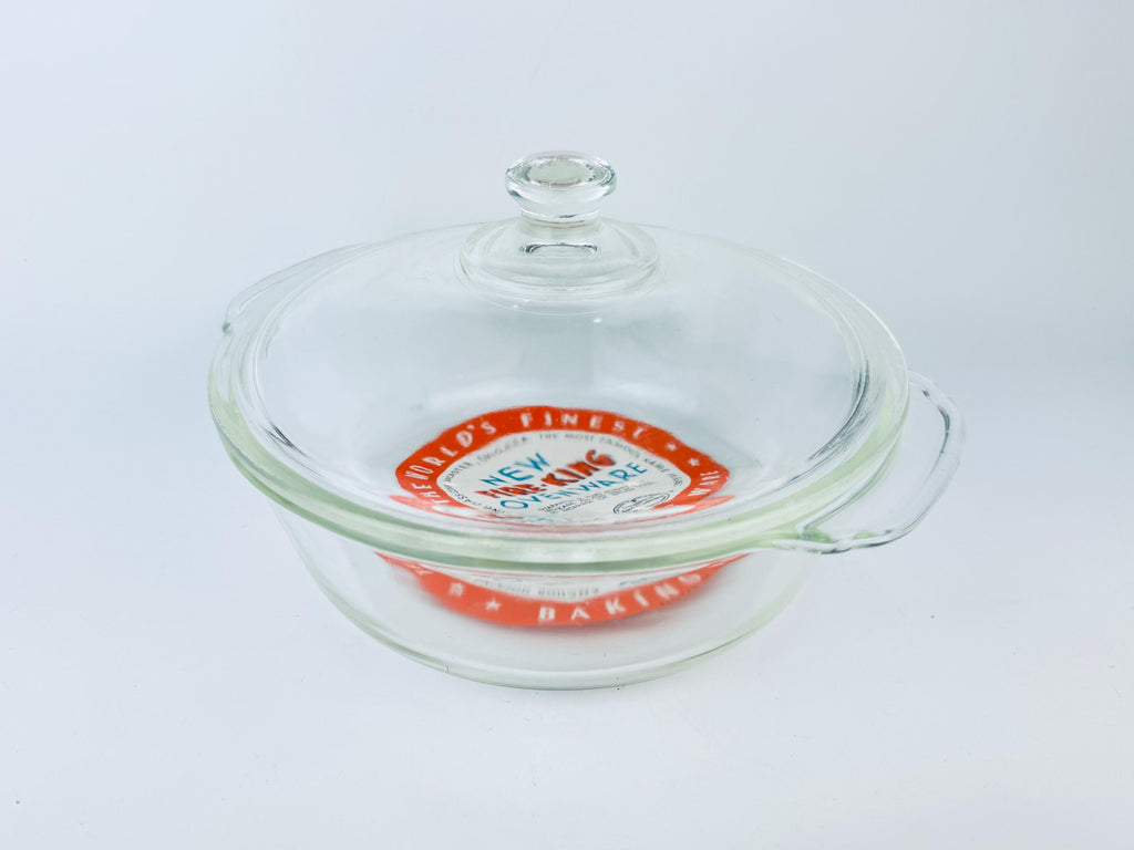 Glass baking dish with a lid featuring a brand logo on a white background
