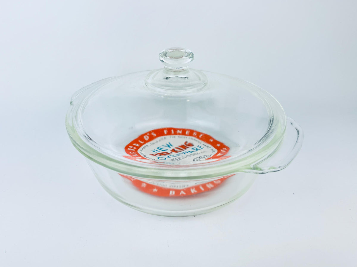 Glass baking dish with a lid featuring a brand logo on a white background