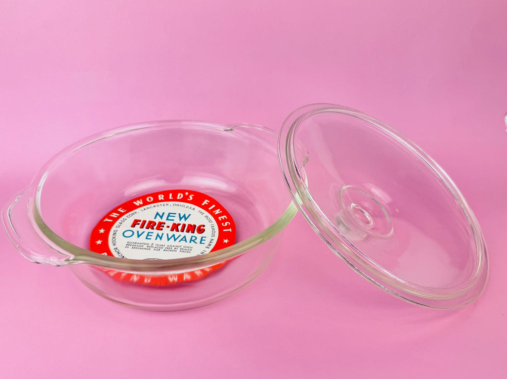 Fire-King ovenware dish with lid on a pink background