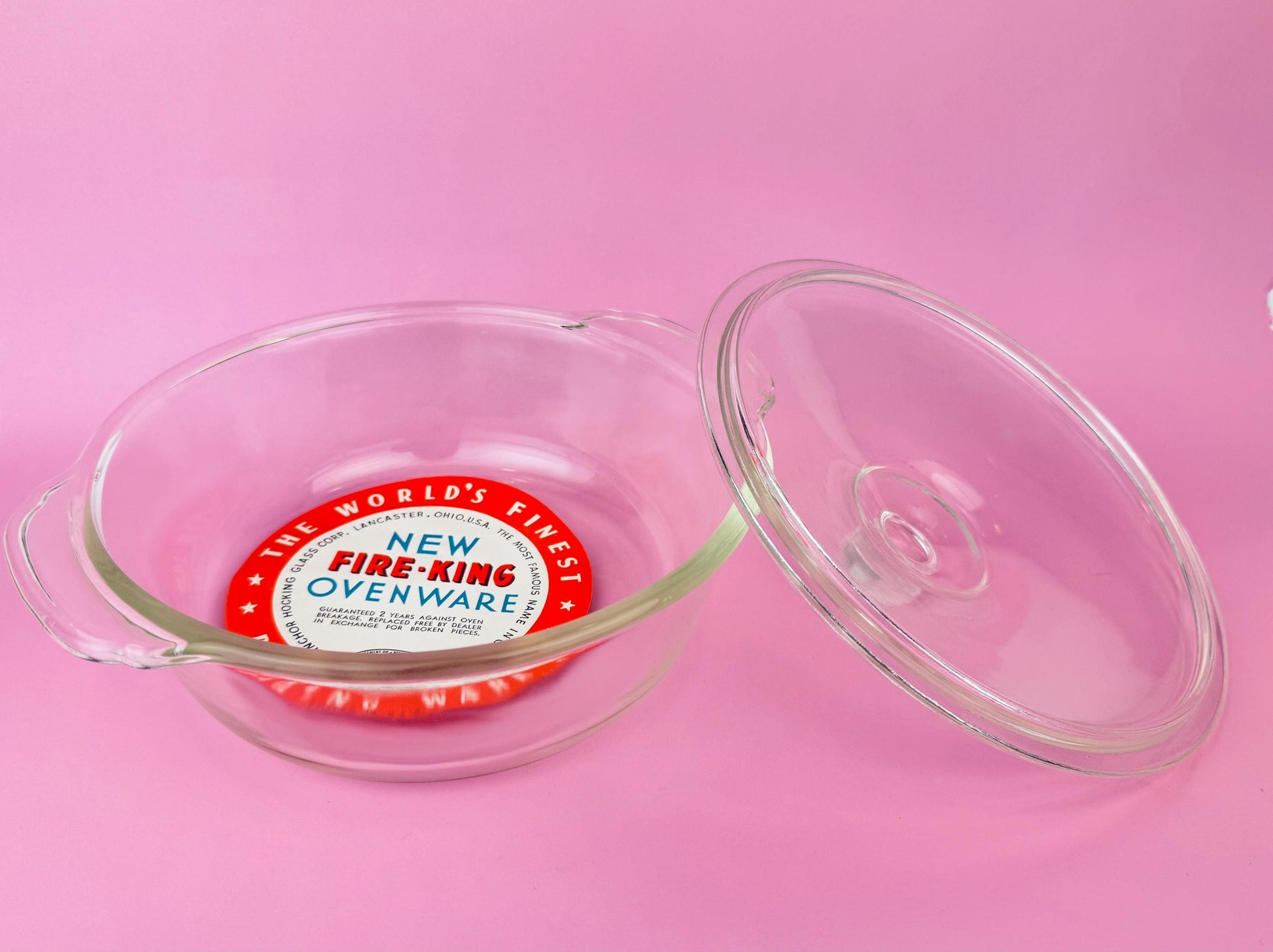 Fire-King ovenware dish with lid on a pink background