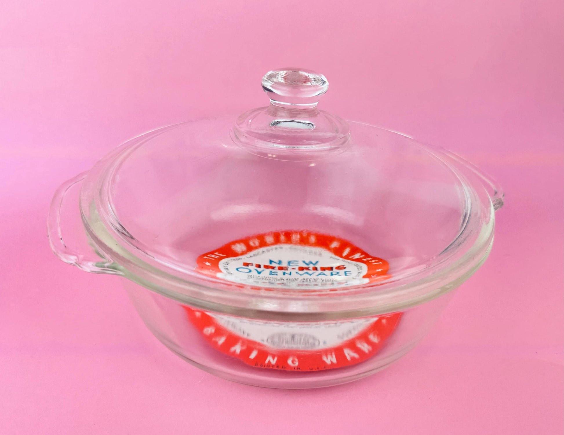 Glass baking dish with a lid on a pink background