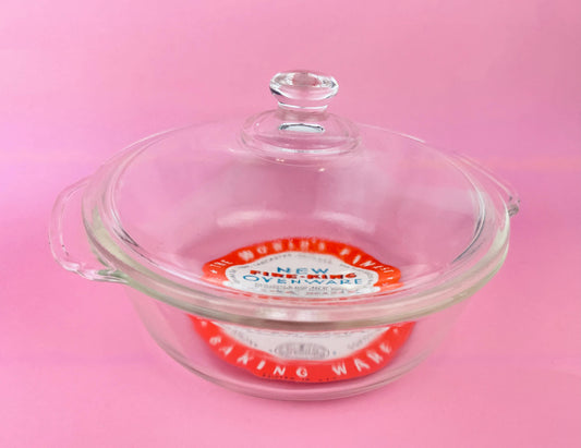 Glass baking dish with a lid on a pink background