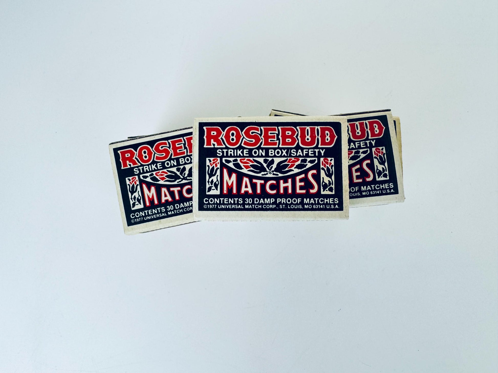 Matchboxes labeled 'Rosebud Matches' on a light gray background