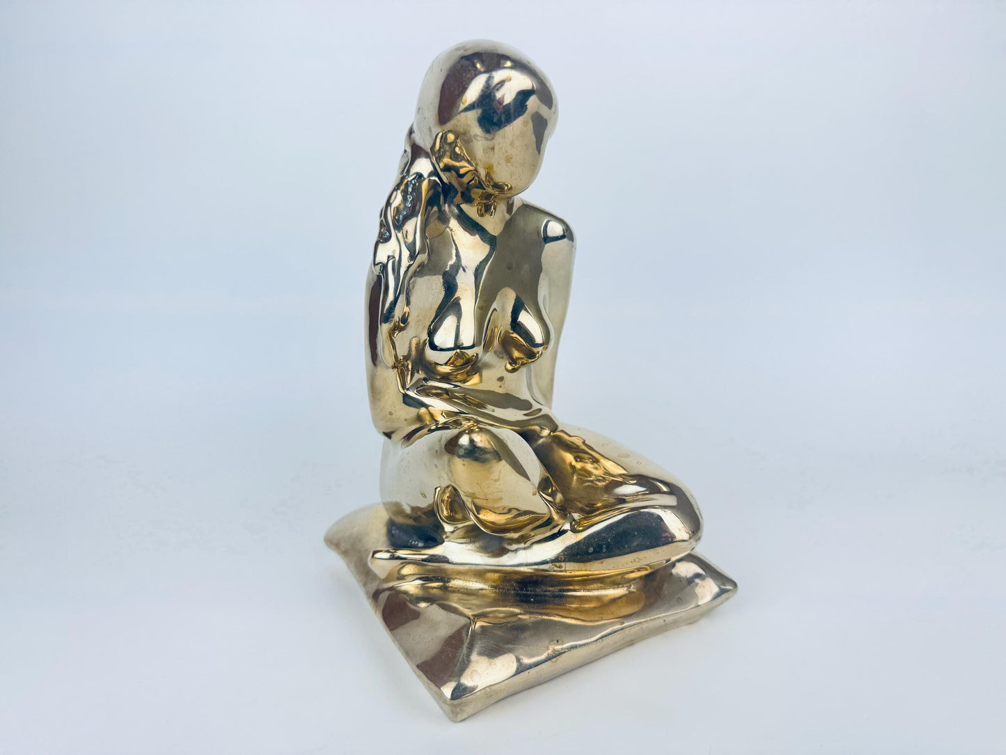 Gold statue of a seated figure on a white background