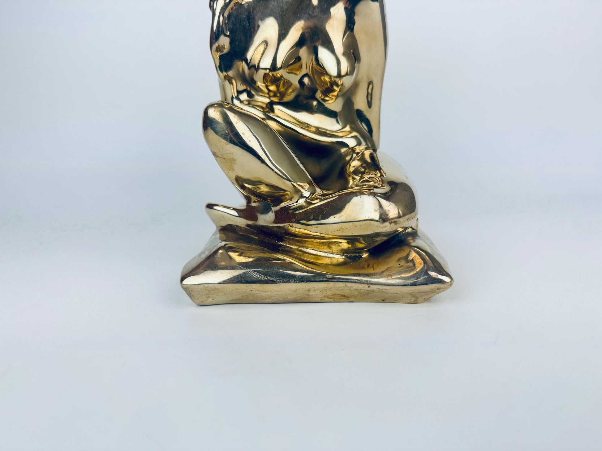 Gold statue of a seated figure on a white background